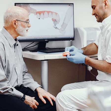 A dentist explaining All-on-4 dental implants to an older patient.