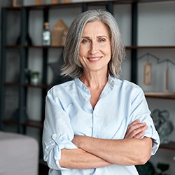 Woman with greying hair smiling with arms crossed
