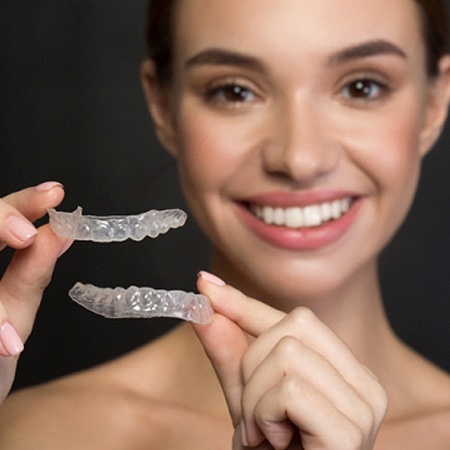 A young female holding top and bottom clear aligners